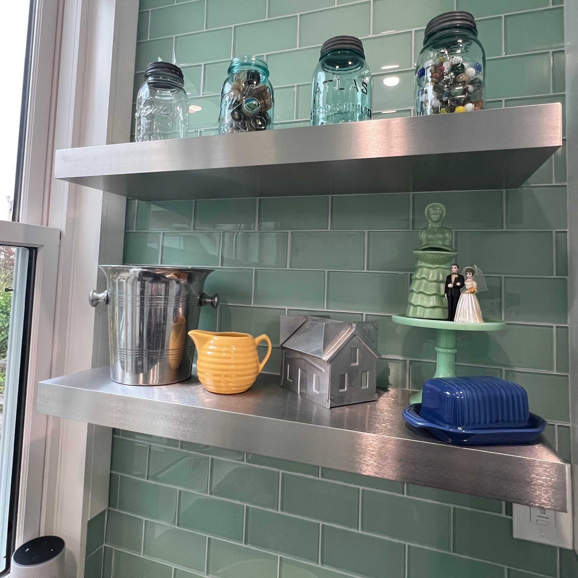 Metal shelves with decorative items against a green tiled wall