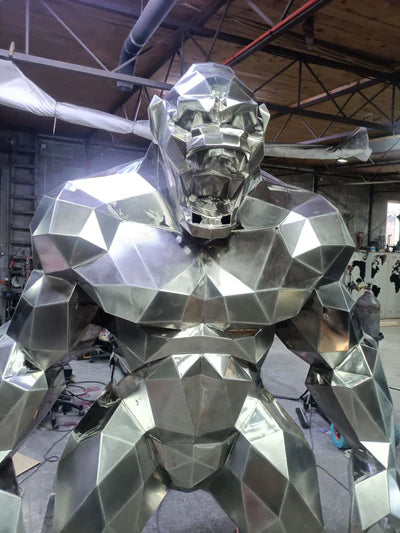 Large metallic sculpture of a humanoid figure in an indoor setting