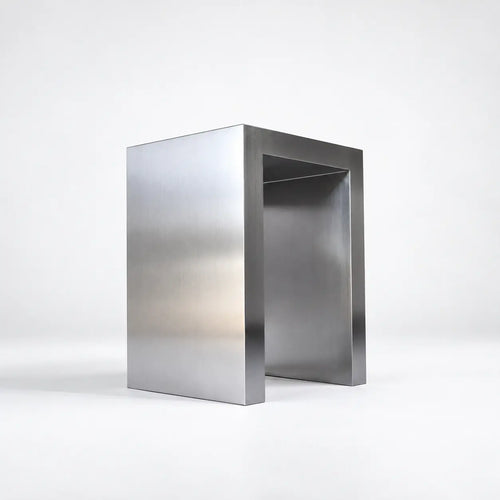 A modern minimalist steel table or console stand with a brushed metal finish, photographed on a clean white studio background.