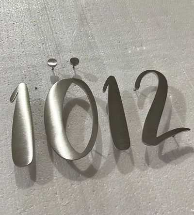 Metallic house numbers '1012' on a textured gray background